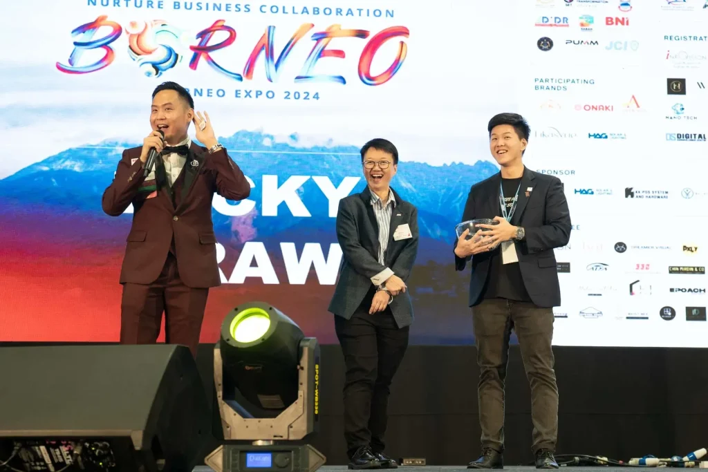 Borneo Expo 2024 Lucky Draw announcement with three presenters on stage at business collaboration event